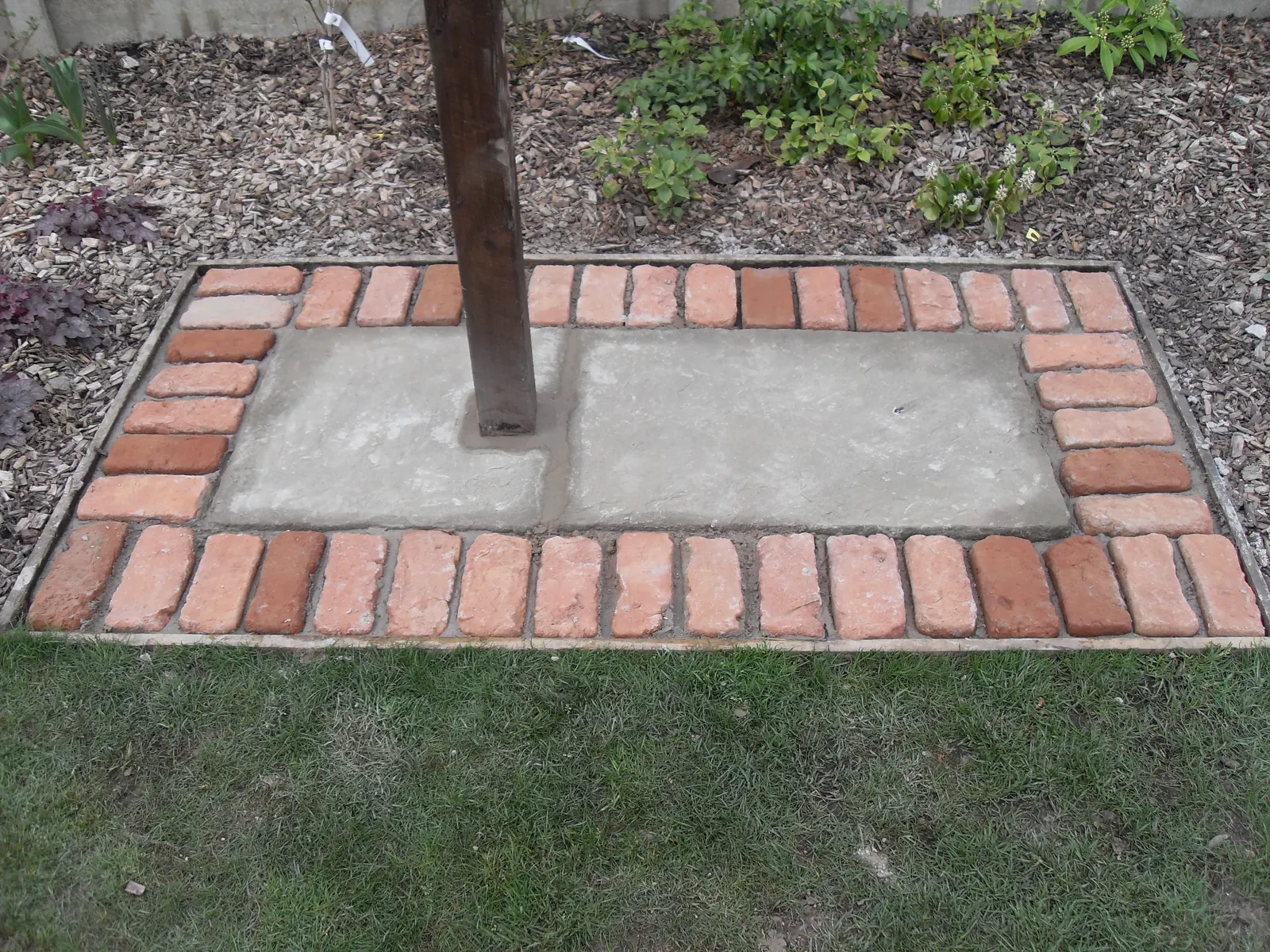 Brick edged paving laid around a timber pergola post