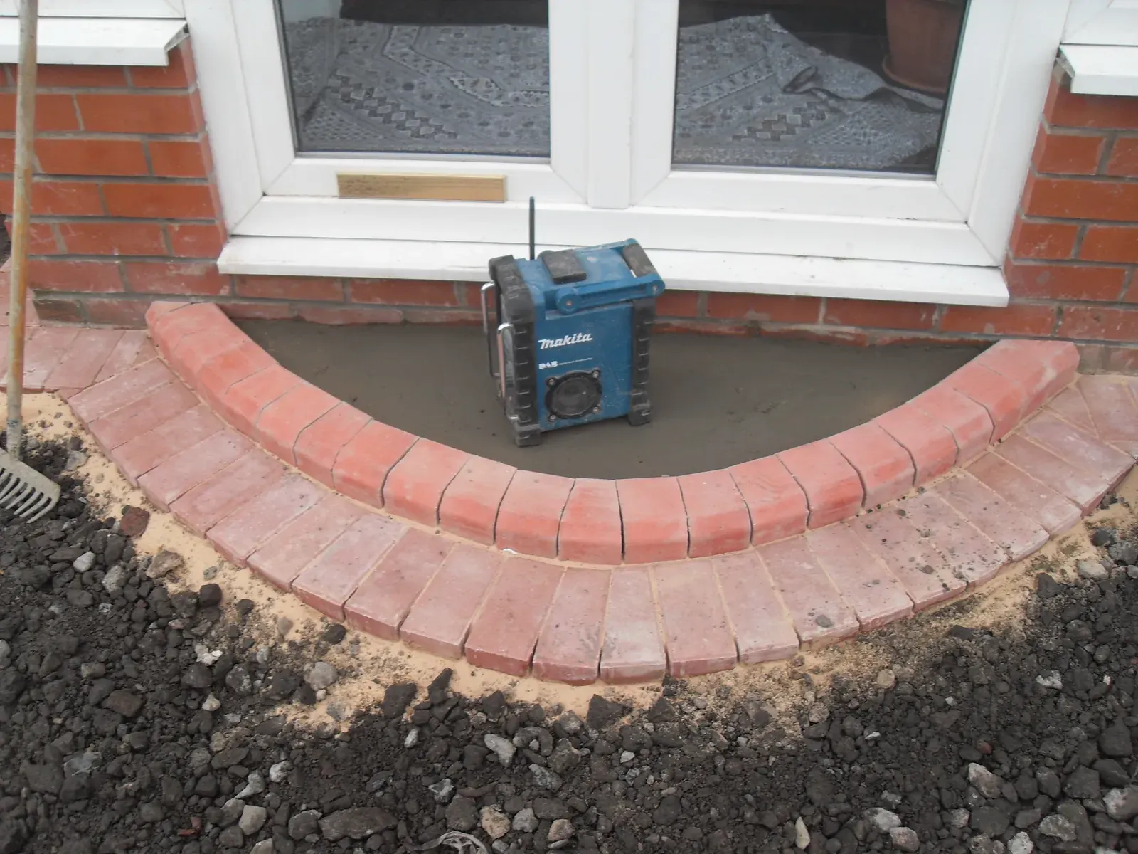 Brick step and curved edging with compactor outside patio doors