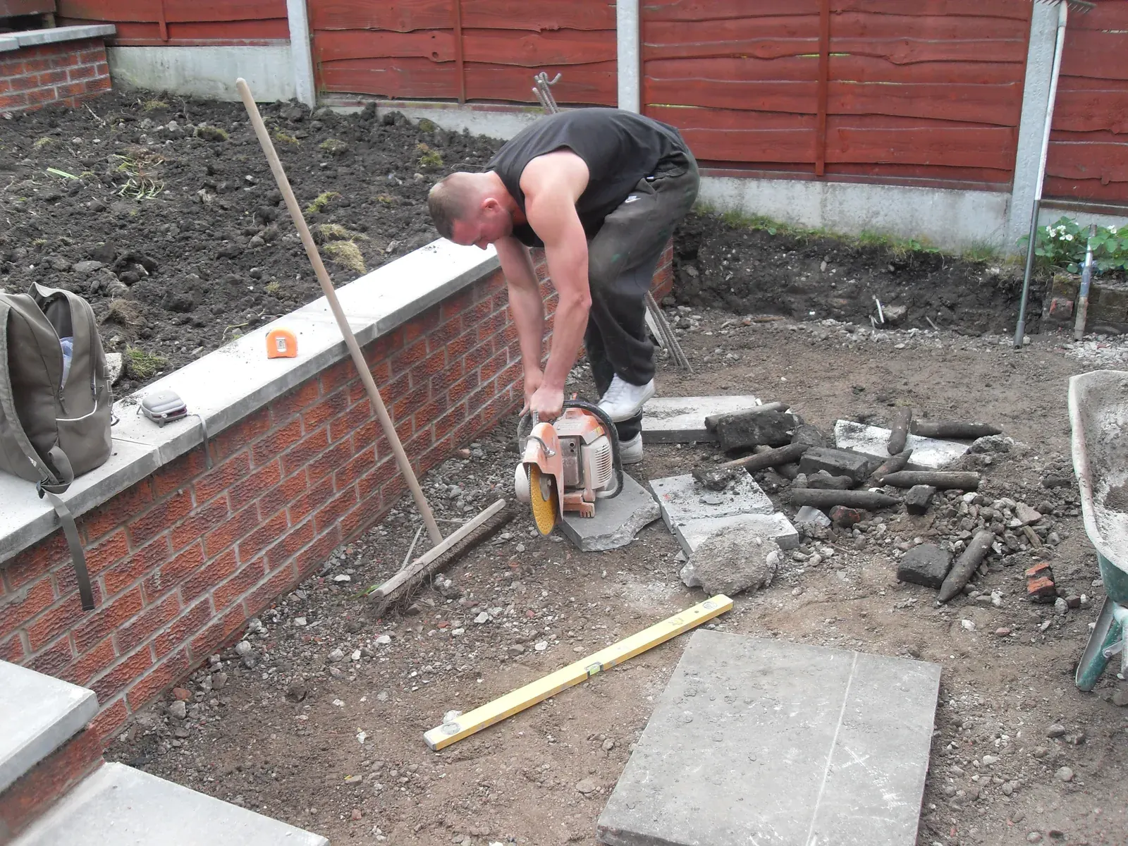 Bricklayer building a red brick garden retaining wall