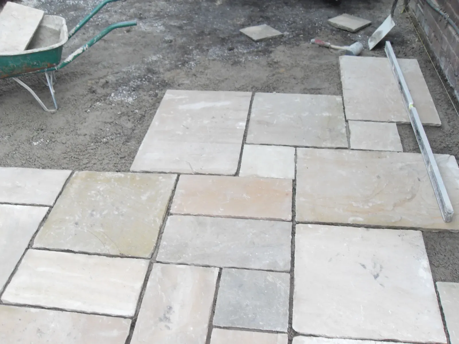 Close up of riven sandstone paving slabs being set to level