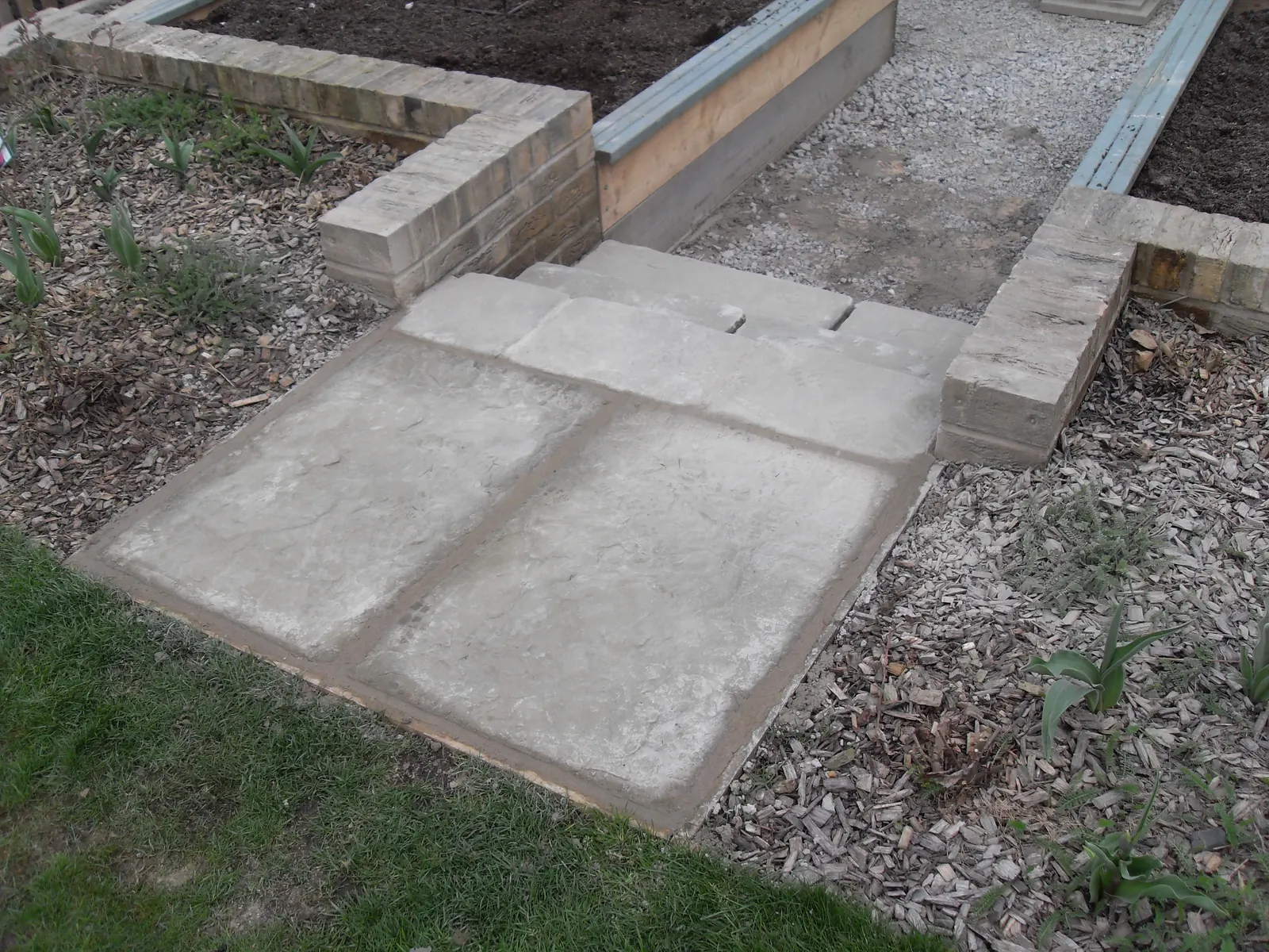 Concrete slab path and brick-edged steps in a rear garden