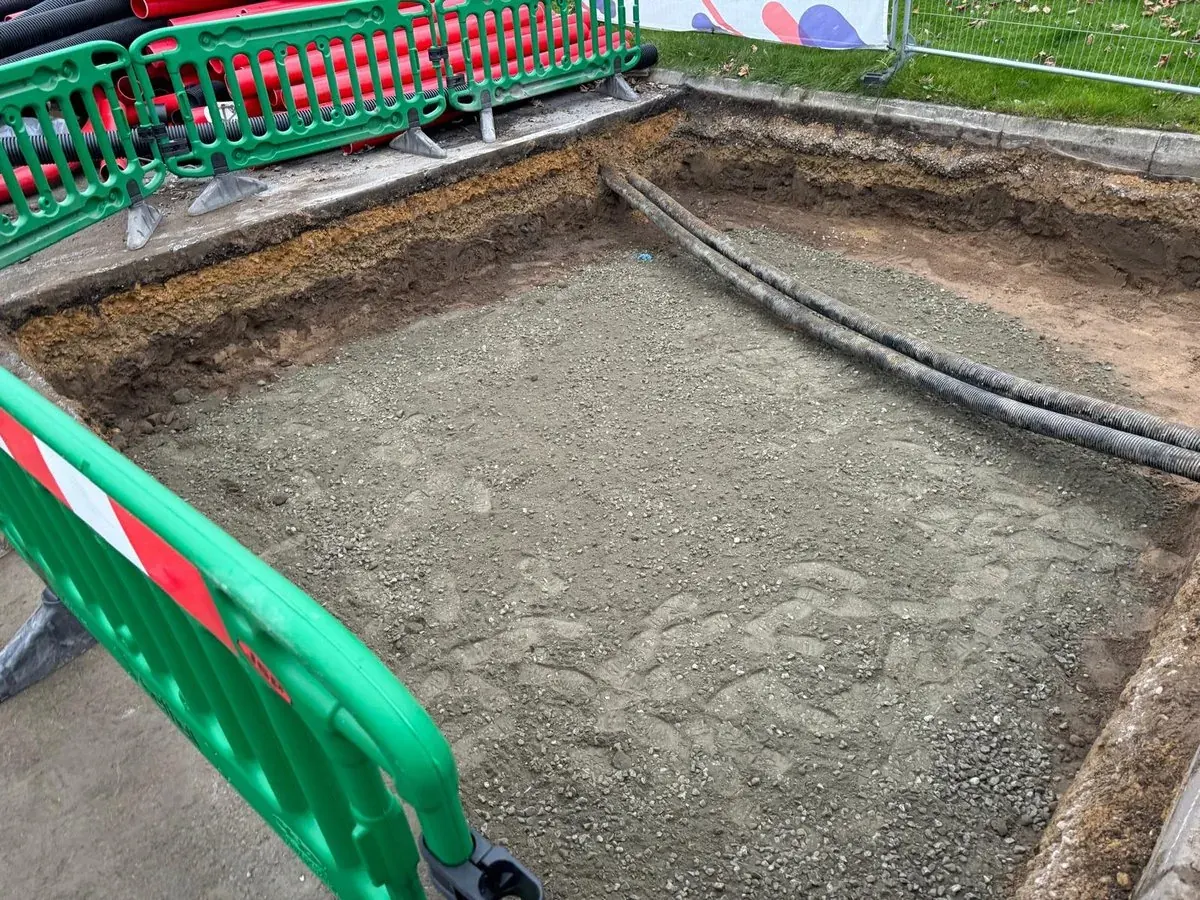 Excavated foundation pit with compacted hardcore base and safety barriers
