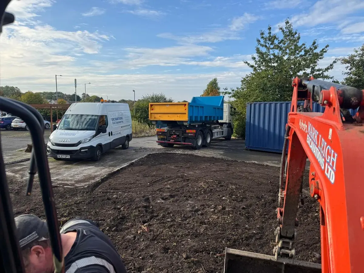 Groundworker operating a tracked excavator while muck away is loaded out