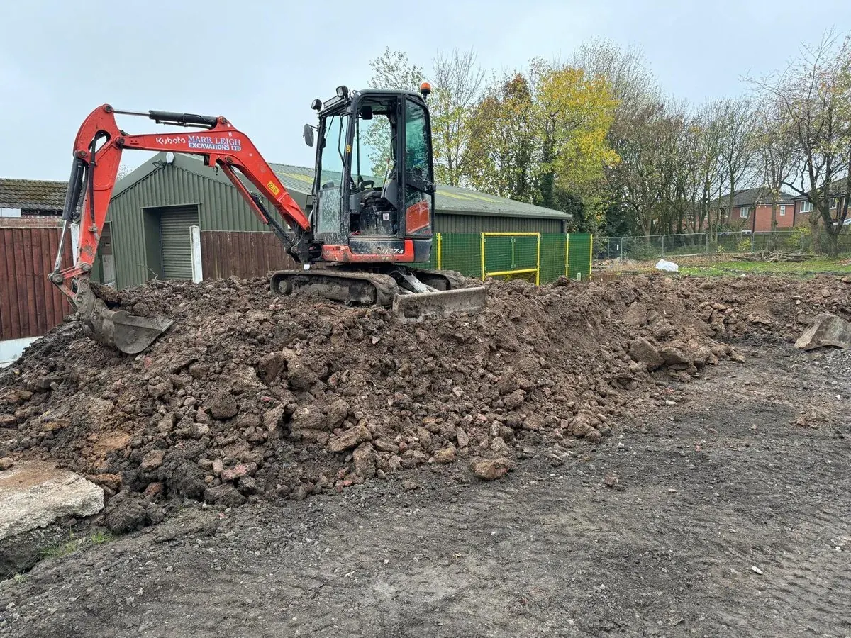 Kubota mini excavator clearing a spoil heap on a commercial site in Manchester
