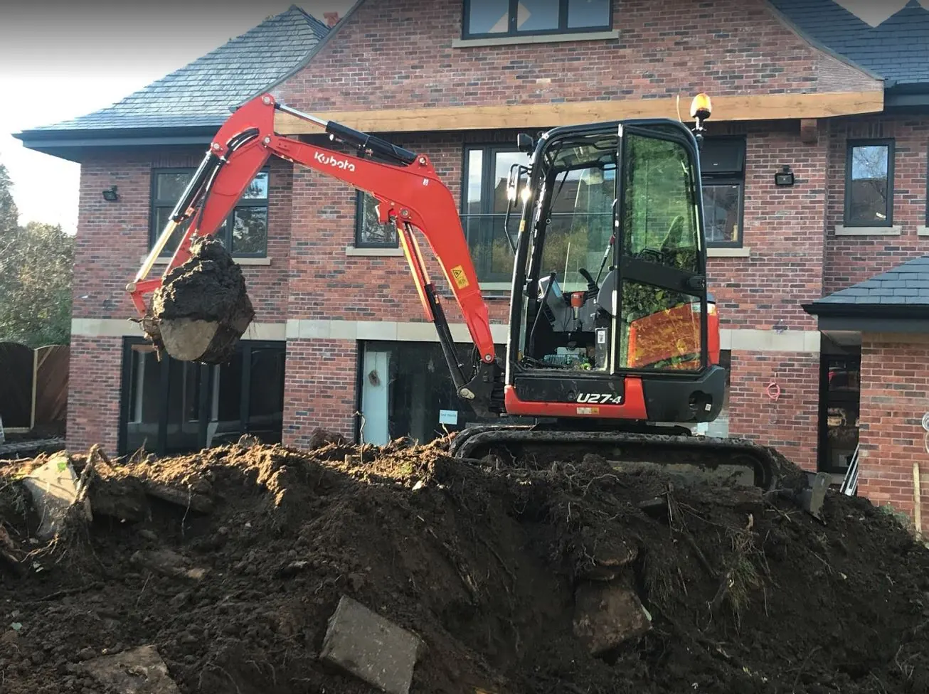 Kubota mini excavator digging out beside a new-build house