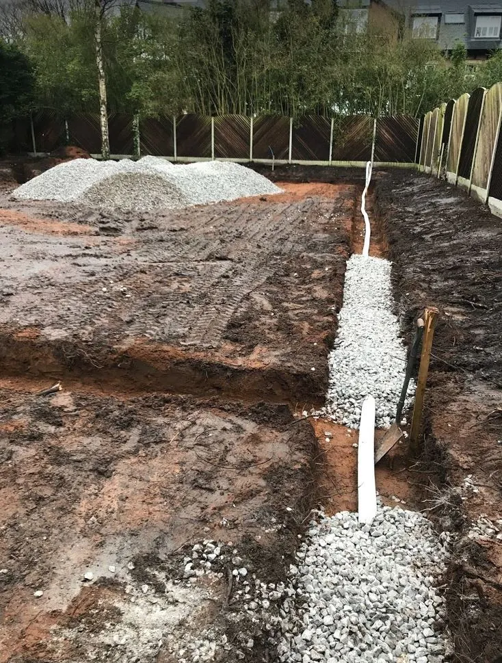 New drainage run bedded in gravel in a garden trench