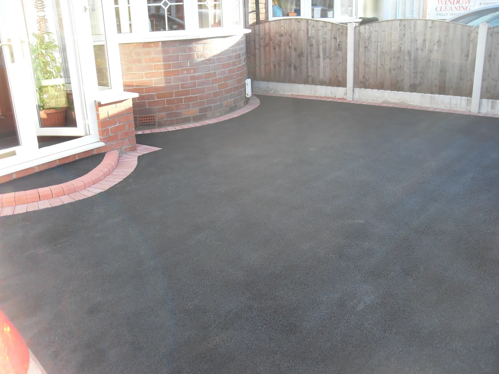 New tarmac driveway sweeping around a curved brick wall