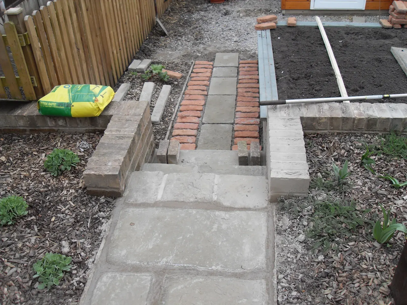 Paved garden path with brick edging and timber sleeper beds