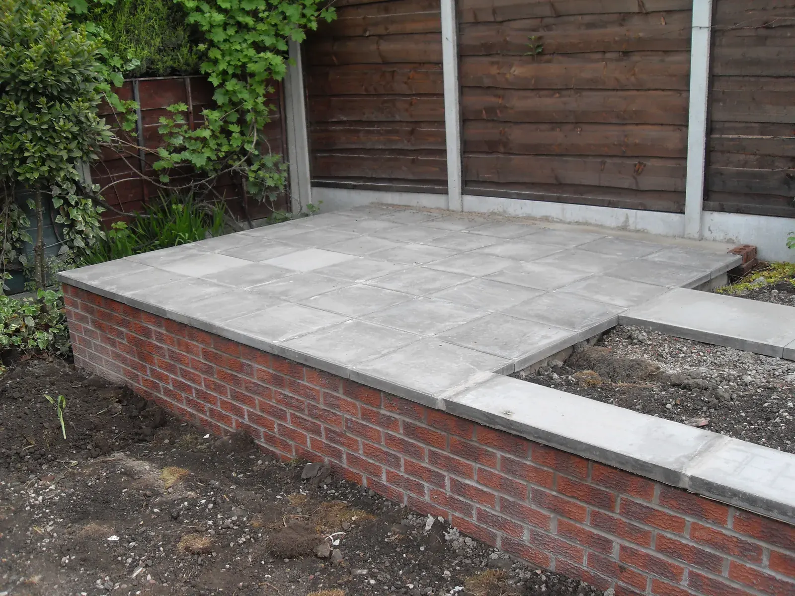 Raised paved patio supported by a new brick retaining wall