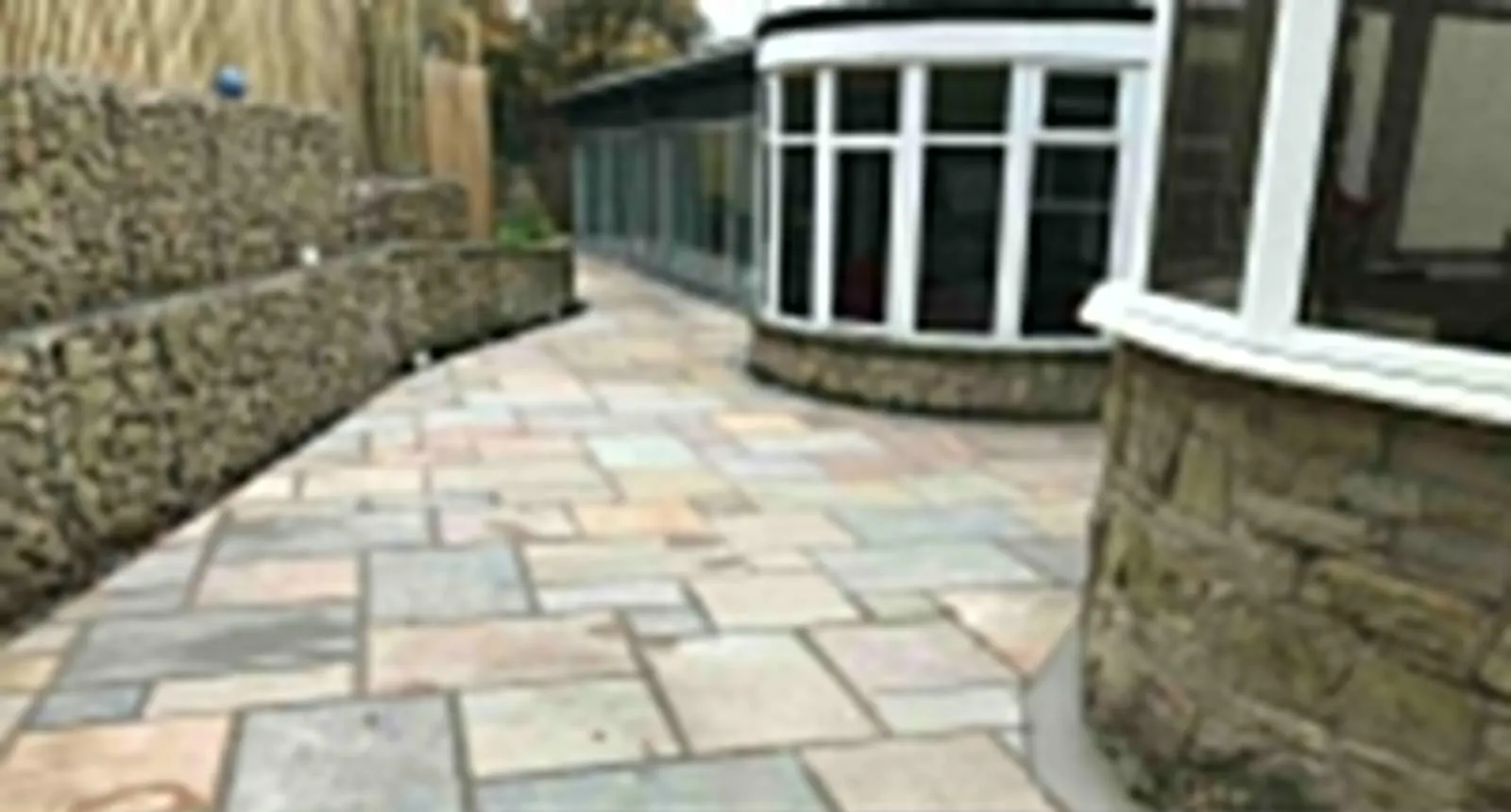 Sandstone patio beside a curved stone garden wall