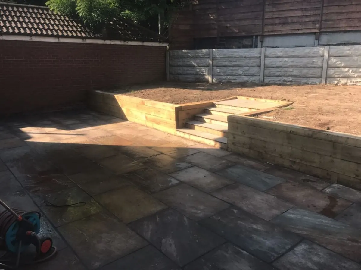 Sandstone patio with sleeper steps up to a raised lawn