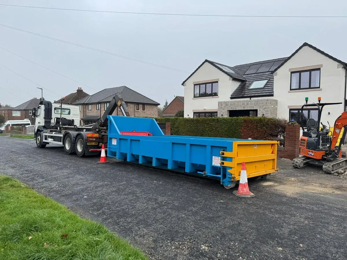 Skip containers and a mini digger set up for groundwork outside houses