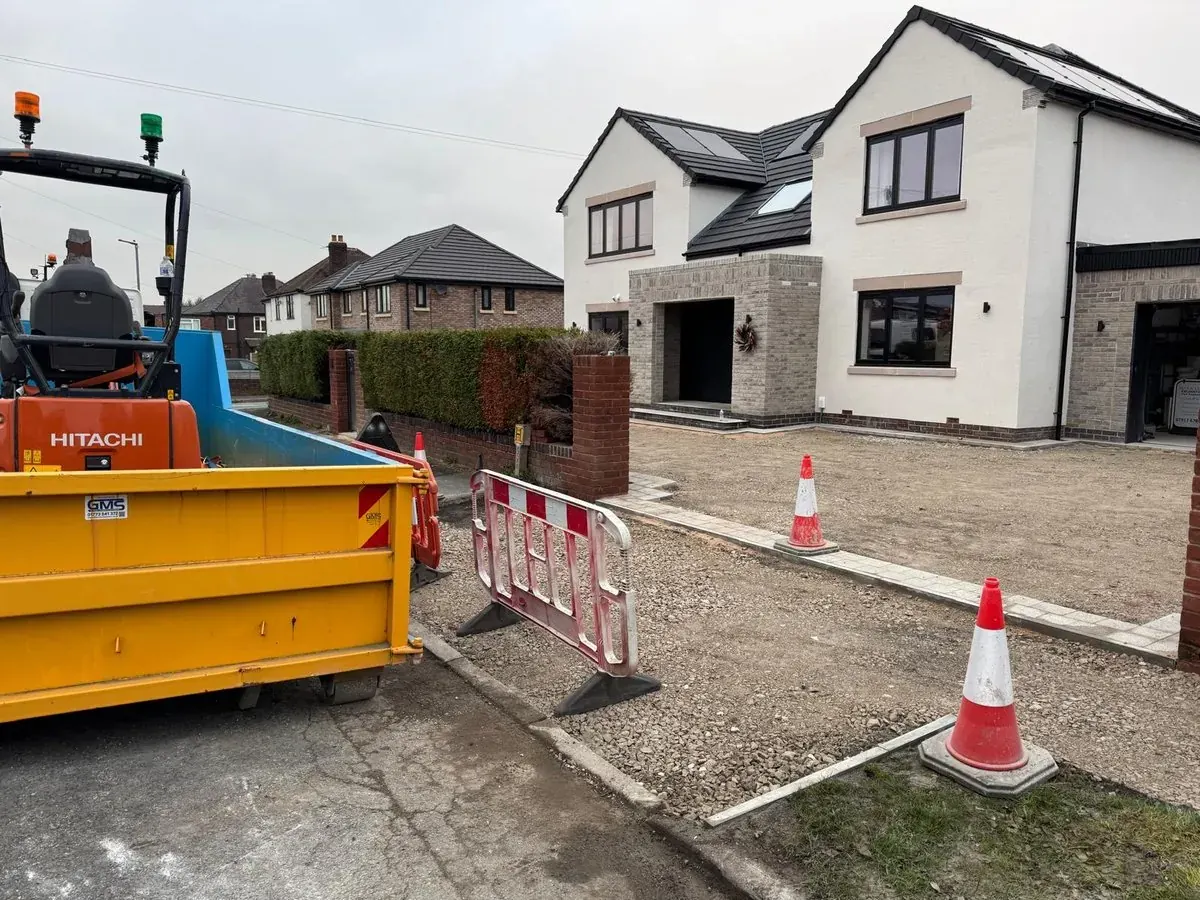 Skip, excavator and completed driveway groundwork at a new build house
