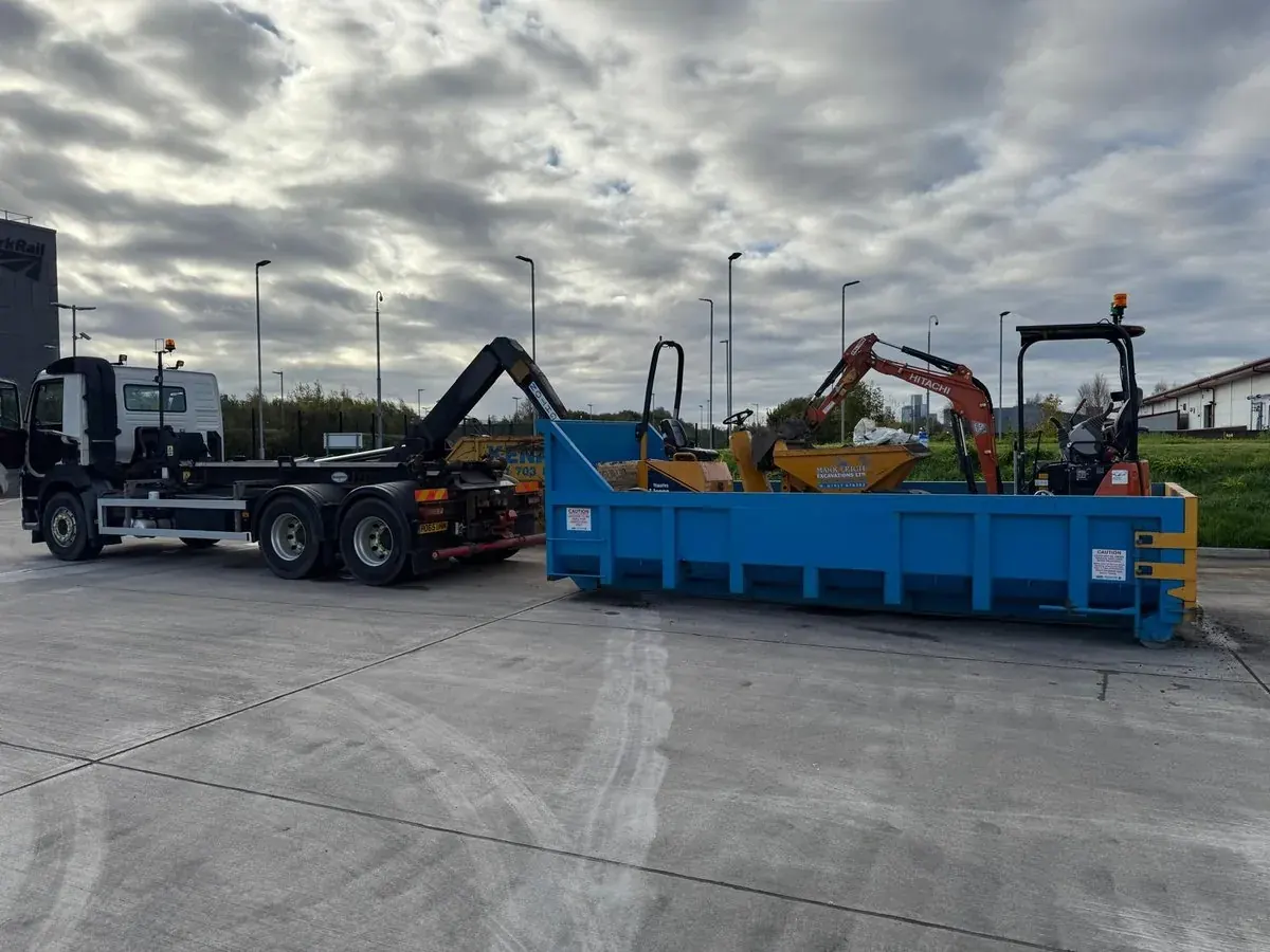 Skip lorry and tracked excavator loaded up at the yard at dusk