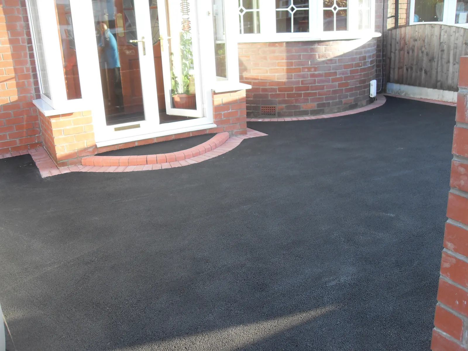Tarmac driveway with brick edging laid up to a house entrance