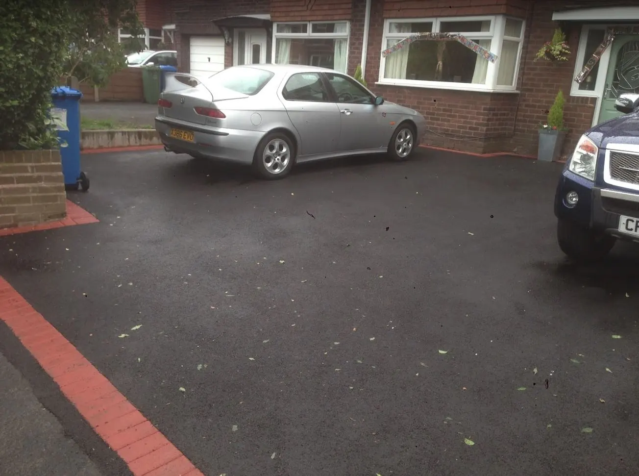 Tarmac driveway edged in red brick in front of a house