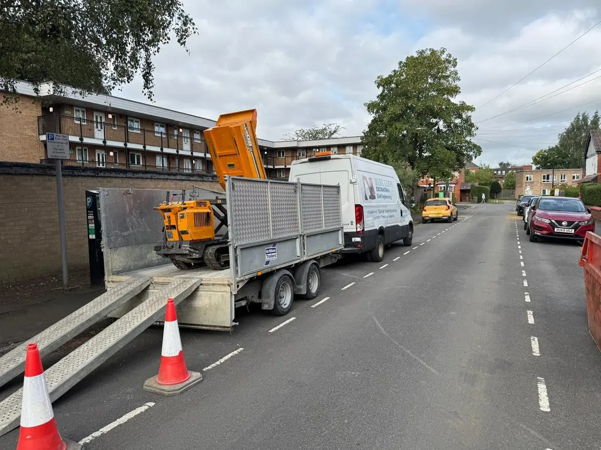 Tipper lorry unloading aggregate on a road with traffic cones in place
